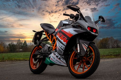 A low angle shot of a parked KTM RC125 Motorcycle on a road under a sunset sky