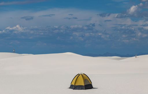 A camping tent in a scenic snowy landscape under the blue cloudy sky