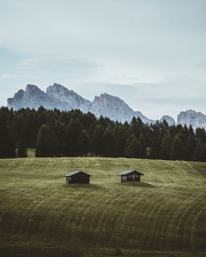 A vertical shot of houses on a flat field near the mountains