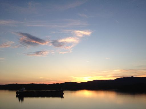 A tranquil scene of a boat docked near the shore at sunset.