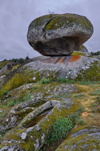 A closeup of outcrops covered in mosses and grass under a cloudy sky in Portugal