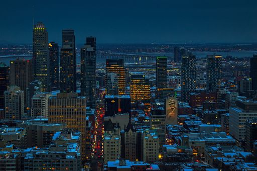 An aerial shot of the Montreal skylines at night in winter with snow covering the rooftops
