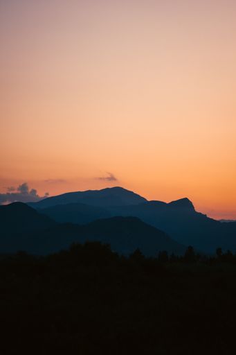 A vertical shot of a breathtaking sunset over the forest surrounded by mountains