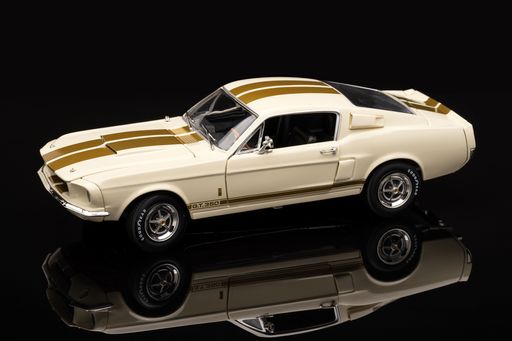 A white Ford Mustang toy on a reflective black surface