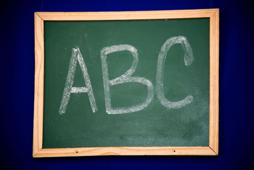 A close-up view of a chalkboard with a stylized ABC written in white chalk on the blackboard surface