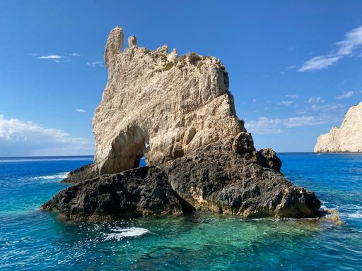 A cliff in the greenish blue sea against the background of the sky. Zakynthos, Greece.