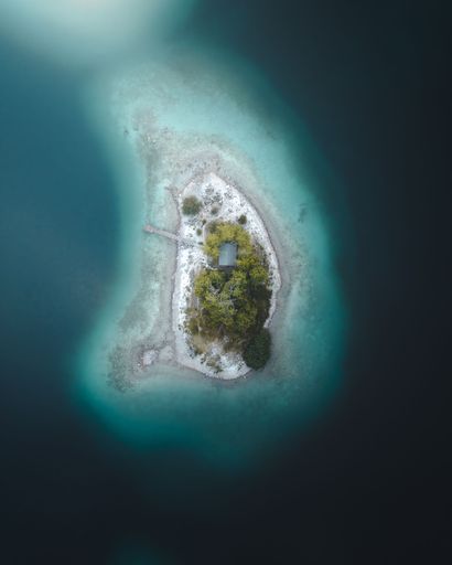 An aerial breathtaking view of a small island surrounded by blue ocean waters
