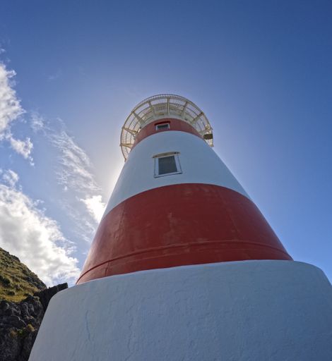 A vertical low-angle shot of a lighthouse against the background of the blue sky.