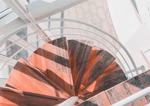 A top view of a round wooden staircase with white railings