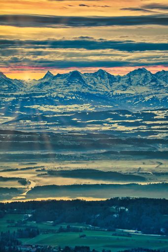 A vertical shot of a mesmerizing landscape with snowy mountains under a cloudy dusk sky