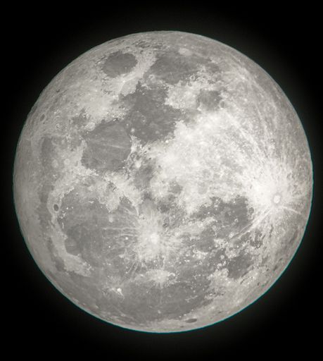A vertical closeup of the full moon in a dark nisht sky