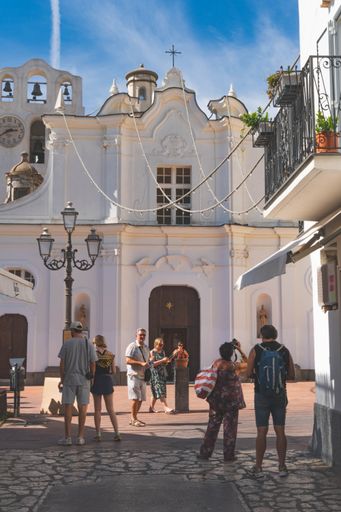 A diverse group of people walking together outside a large building with a clock tower visible in the background