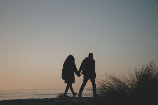A romantic couple strolling along a tropical beach, holding hands and enjoying the sunset