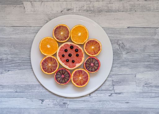 A top view of various halved citrus fruits arranged in a circle on a plate