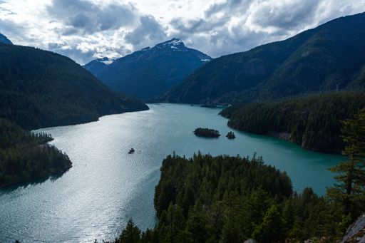 A high angle shot of a river between hills and forests on a cloudy day