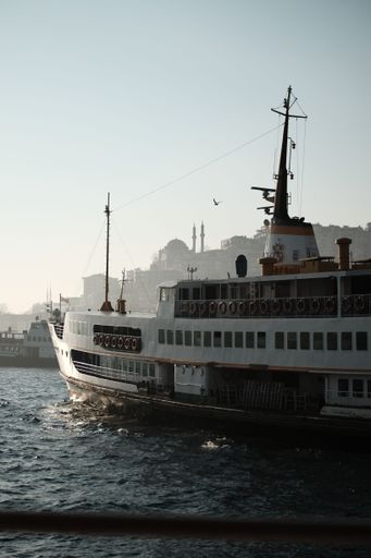 A majestic ship sailing on the Bosphorus strait in Istanbul, Turkey, against a beautiful skyline of the city's iconic architecture