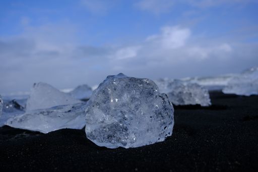 A closeup shot of a piece ice on a shore under the blue sky and clouds