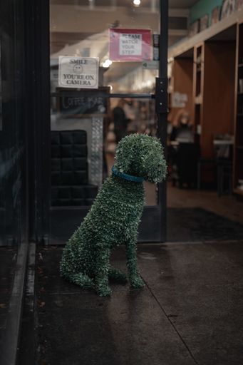 A vertical shot of a topiary dog in front of a cafe