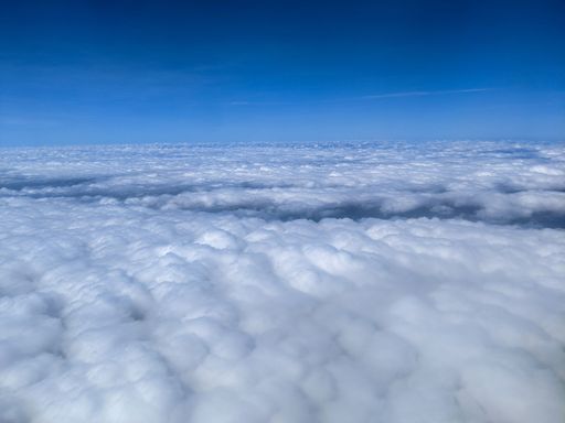 An aerial view of a blue sky dotted with white, fluffy clouds.
