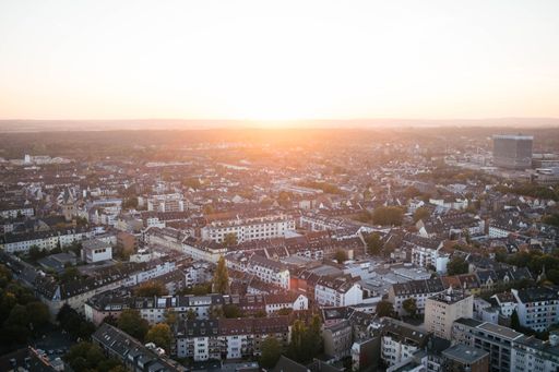 A horizontal shot of a sunset over a large city. It's summer and the sun is shining in Cologne.