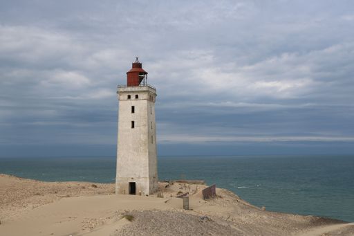 A beautiful view of the Rubjerg Knude lighthouse on the cliff near the tranquil sea in Lokken, Denmark