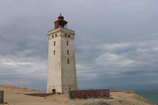 Abandoned lighthouse Rubjerg Knude in the sand dunes against a cloudy sky