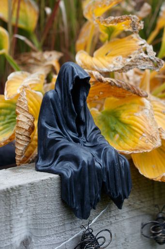 A menacing statue of the Grim Reaper, cloaked in a long, flowing robe