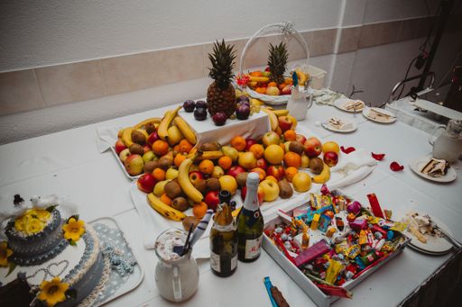 A white table with fruits and desserts arranged on it for a reception