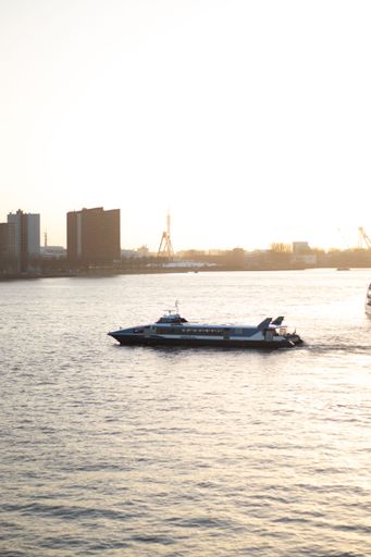 A vertical shot of a boat sailing on the Nieuwe Maas river in Rotterdam