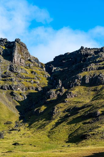 A vertical shot of mountains against a blue sky on a sunny day