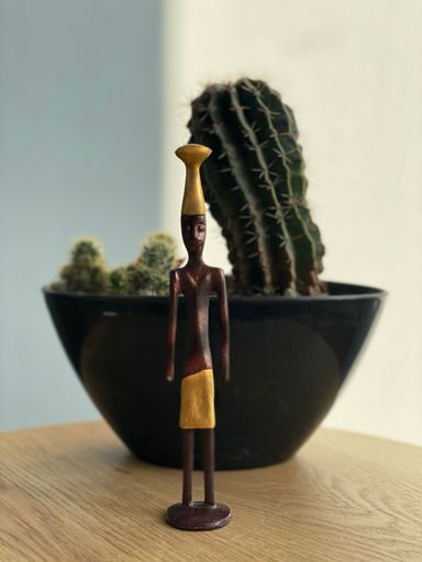 A vertical shot of a statue of an African man with a cactus in the background