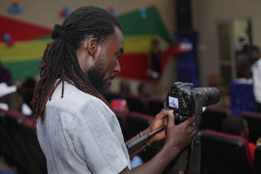 An African American man using a camera on a tripod to film a conference