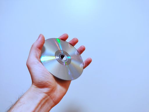 A closeup view of a person holding a compact disk in his hands on a light blue background