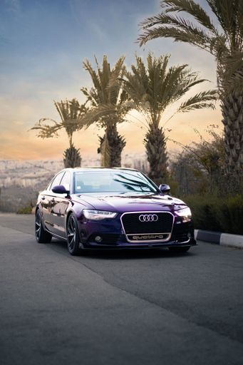 A vertical shot of a luxury and beautiful purple Audi A6 car driving on the highway