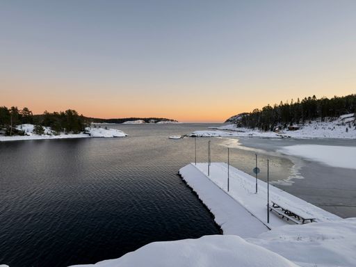 A scenic winter landscape featuring a large body of water covered in a blanket of snow