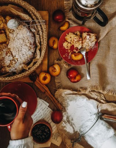 A vertical top view of a woman holding a cup of coffee with a pie in a basket in the background