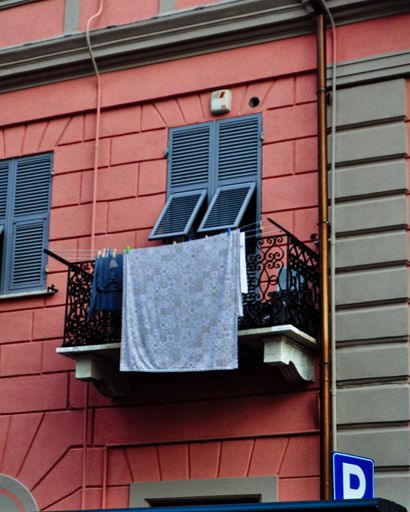 A vertical shot of the red building with balconies and clothes drying on a line