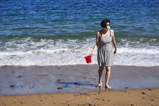 A view of a Hispanic woman enjoying her time at the beach with a mask during a pandemic