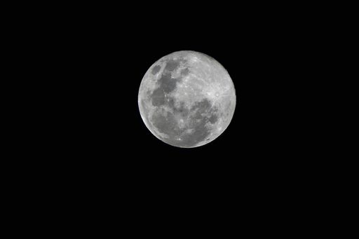 A scenic shot of a full moon against the dark night sky