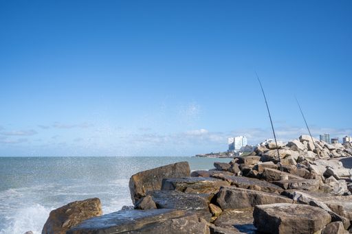 A beautiful shot of the ocean with waves splashing on the rocks in Mar del plata, Buenos Aires