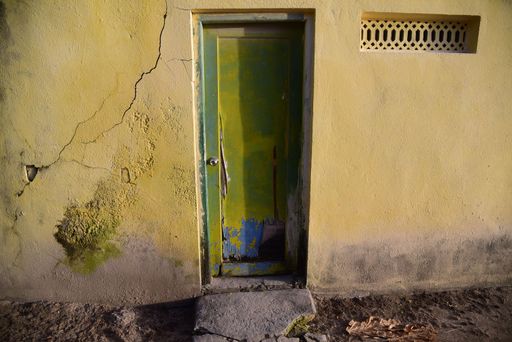A close-up of an old rustic door and cracked wall in sunlight