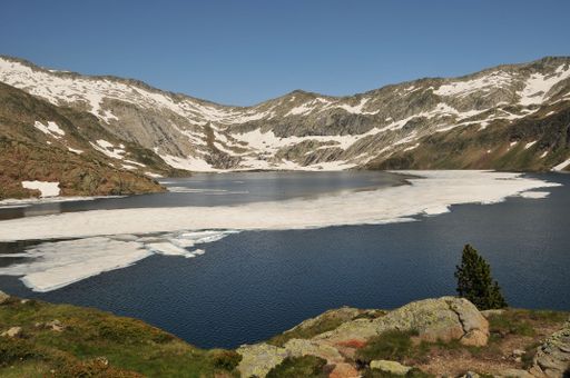 A large body of water surrounded by snow covered mountains and grass