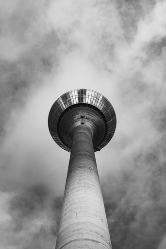 A low angle grayscale shot of a television tower in Dusseldorf, Germany under a beautiful cloudscape