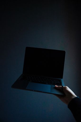A vertical shot of a person holding a modern laptop