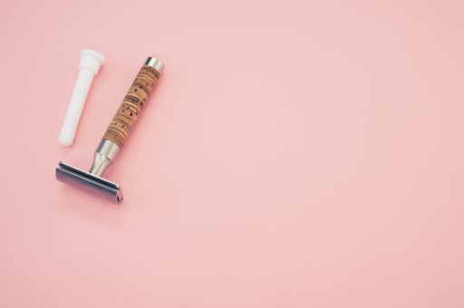 A high angle shot of an old razor on a pink surface