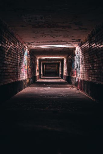 A vertical shot of an old empty underground corridor tunnel of an urban city with graffiti walls