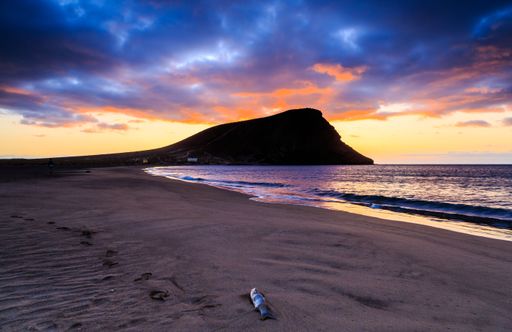 A beautiful shot of a bright sunset sky over a seashore with a cliff on Tenerife Island