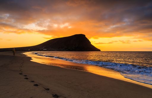 A beautiful shot of a bright sunset sky over a seashore with a cliff on Tenerife Island