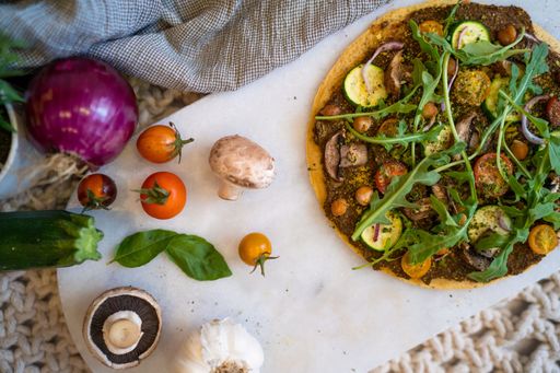 A top view of a tasty big vegan pizza with cucumber, mushroom, tomatoes