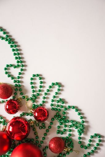 A top view of two red and green Christmas ornaments on a white background with plenty of copy space for text or other content